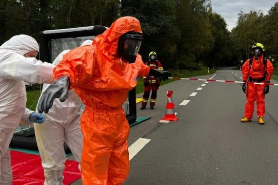 Feuerwehr sichert vier Behälter mit unbekannter ätzender Flüssigkeit am Waldrand; Polizei und Einsatzfahrzeuge.
