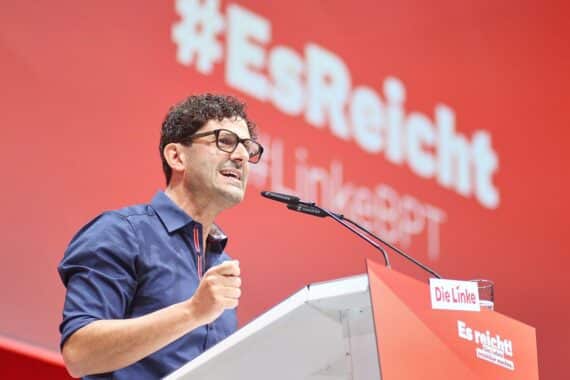Luigi Pantisano bei einem politischen Auftritt, kritisch gestikulierend vor Mikrofonen.
