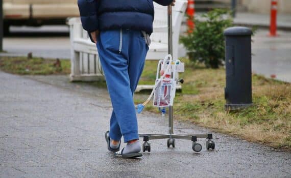 Ein Patient mit Infusionsständer auf einem Krankenhausflur als Symbol für stationäre Behandlungen in Deutschland.