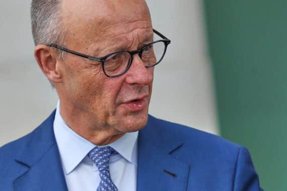 Friedrich Merz bei einer Rede in Seoul, im Hintergrund die Flaggen Deutschlands und Südkoreas.