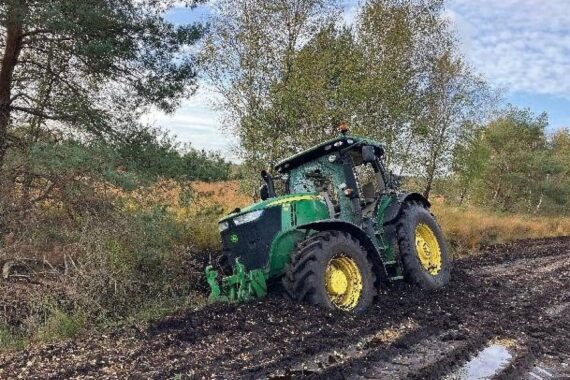 Ein im Moor festgefahrener John-Deere-Traktor mit eingeschlagenen Scheiben im Steinfelder Abbaugebiet bei Bülstedt.