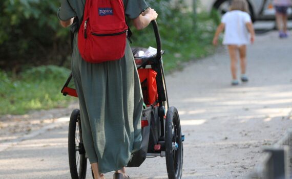 Mutter und Vater mit Kleinkind und Kinderwagen als Symbol für partnerschaftliche Elternzeit und die Elterngeldreform.