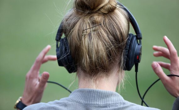 Frau mit Kopfhörern im Musik-Kontext; Hinweis auf aktuelle deutsche Album- und Single-Charts.