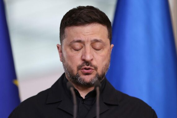 Wolodymyr Selenskyj im Archivfoto, Donald Trump im Hintergrund: US-Kritik und Ablösungsforderung.