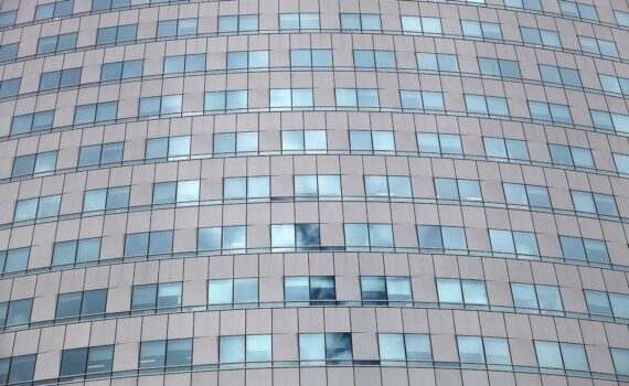 Unternehmer am Schreibtisch vor hohen Aktenstapeln, symbolisch für die wachsende Bürokratiebelastung deutscher Unternehmen.